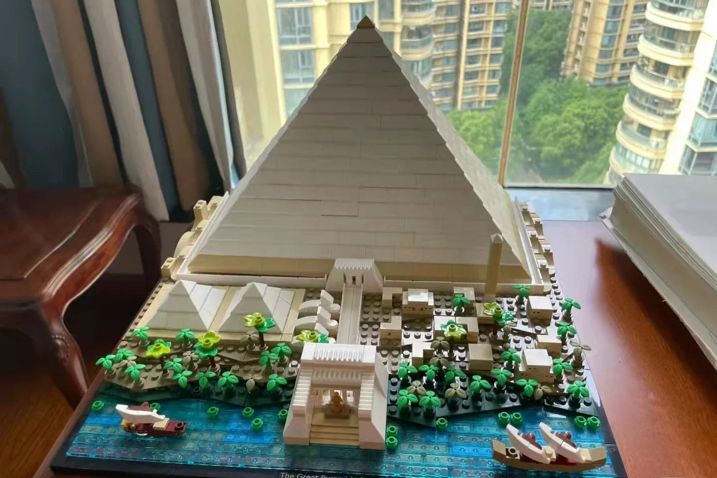 Front view of complete pyramid building set displayed near window with city view