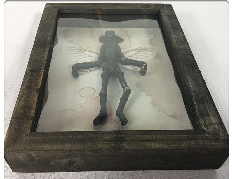 Top-down view of mummified fairy figure in aged wooden shadow box on light surface