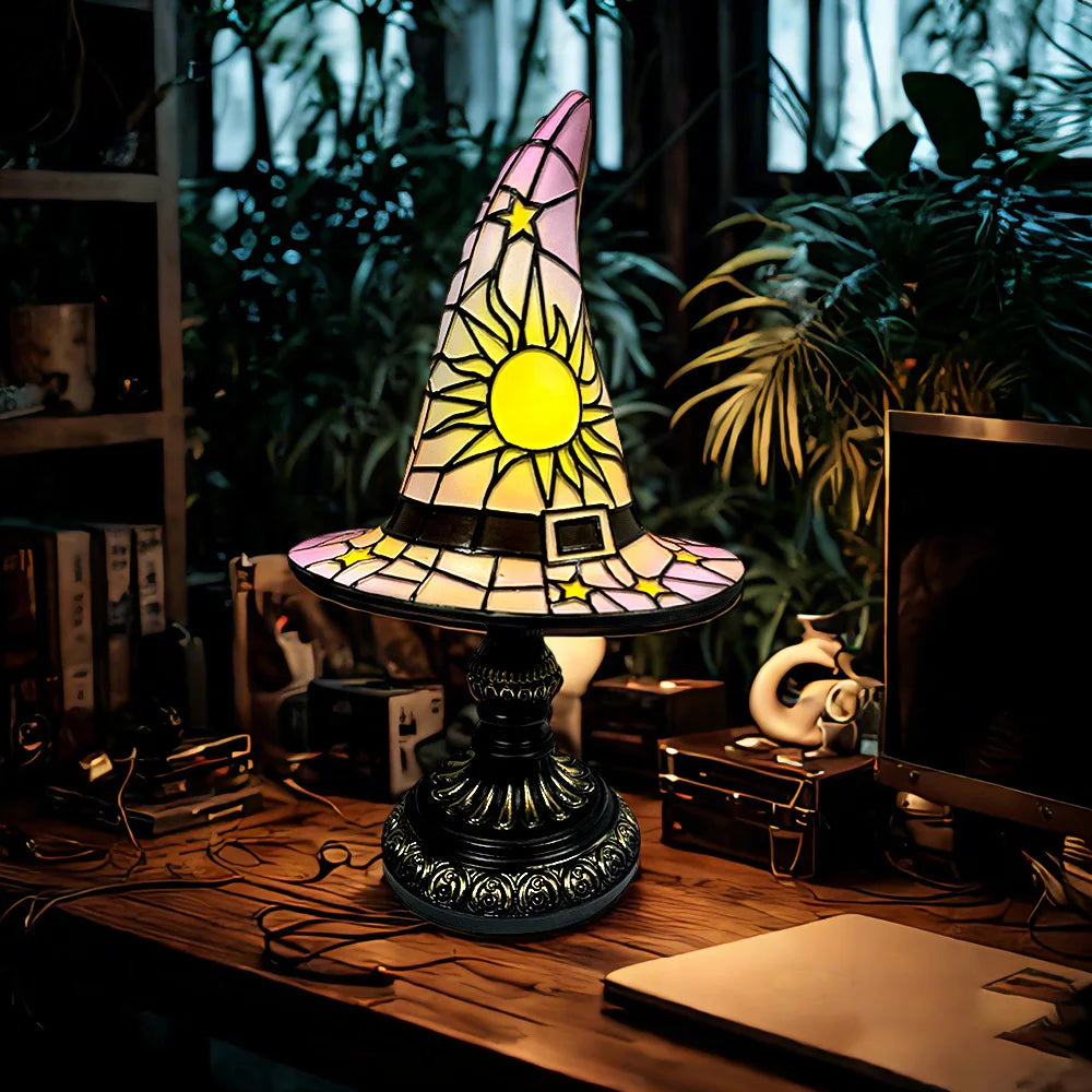 Soft pastel stained glass witch hat lamp in white and pink shades lit beside plants and books