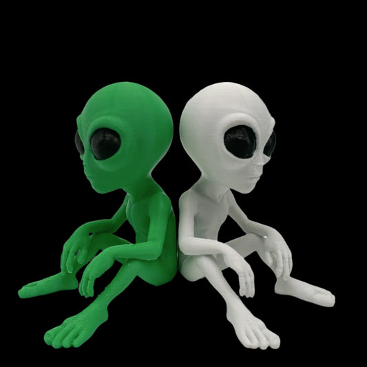 Green and grey 3d printed alien figurines on a black background