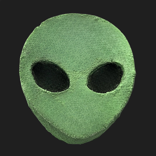 Green alien head bath bomb with classic black oval eyes on dark background
