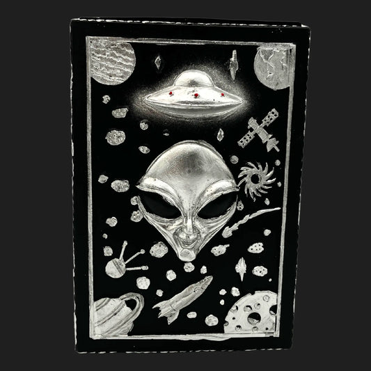 Alien trinket box lid with extraterrestrial face, UFO, planets, rockets, and galaxy designs in silver on black