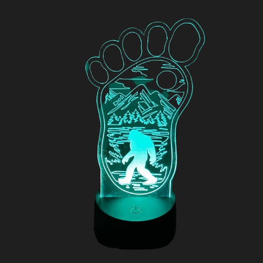 Bigfoot footprint LED lamp glowing blue with mountain forest and Sasquatch silhouette.