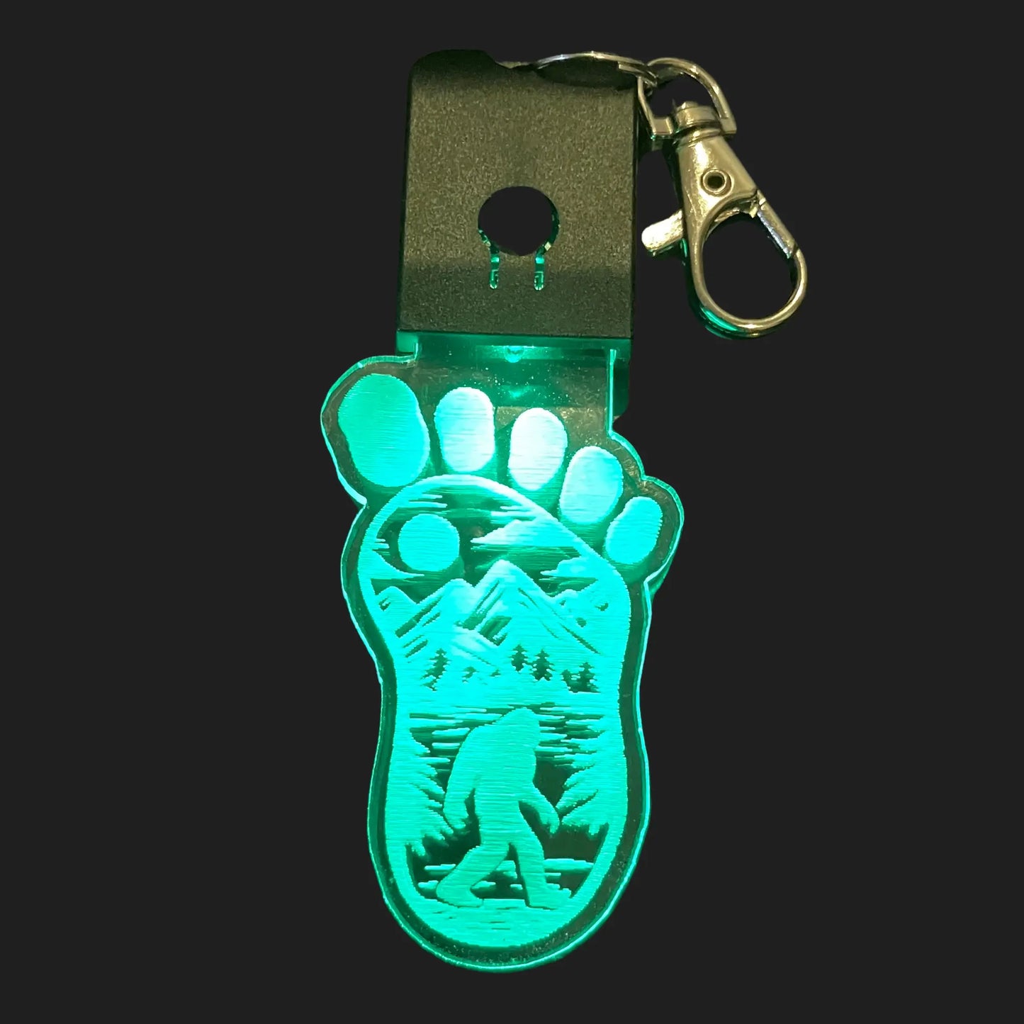 Bigfoot footprint LED keychain glowing green with walking Sasquatch design