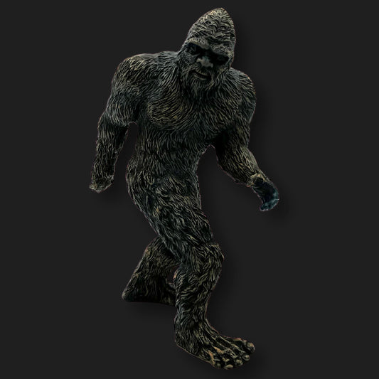 Dark Bigfoot figurine in a walking pose with detailed fur texture, front angle.
