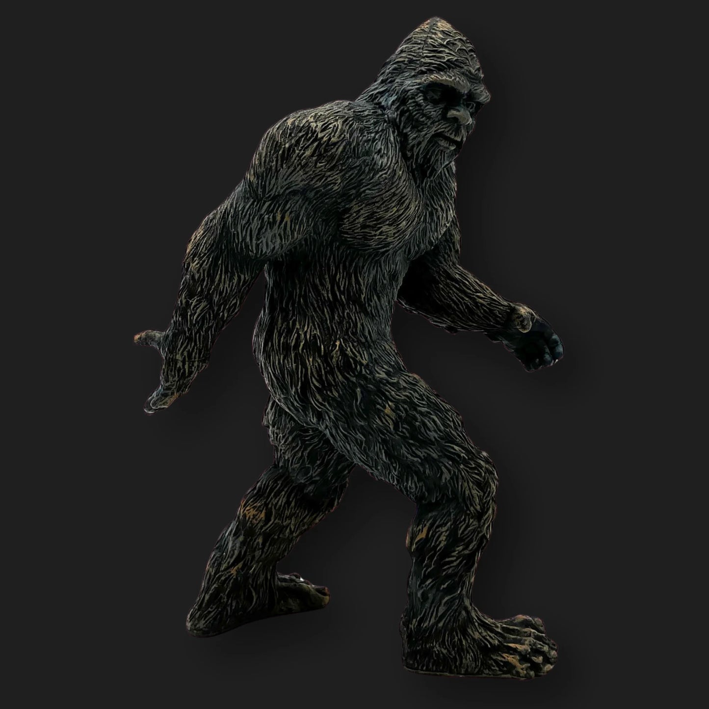 Bigfoot figurine side profile, mid-stride with muscular arms and shaggy fur.