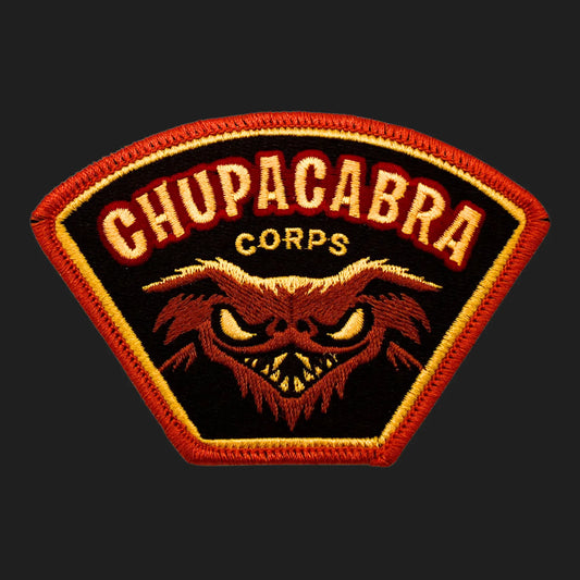 Embroidered Chupacabra Corps iron-on patch, 4 x 2.75 inches, featuring snarling goat-sucker cryptid face in red and gold.