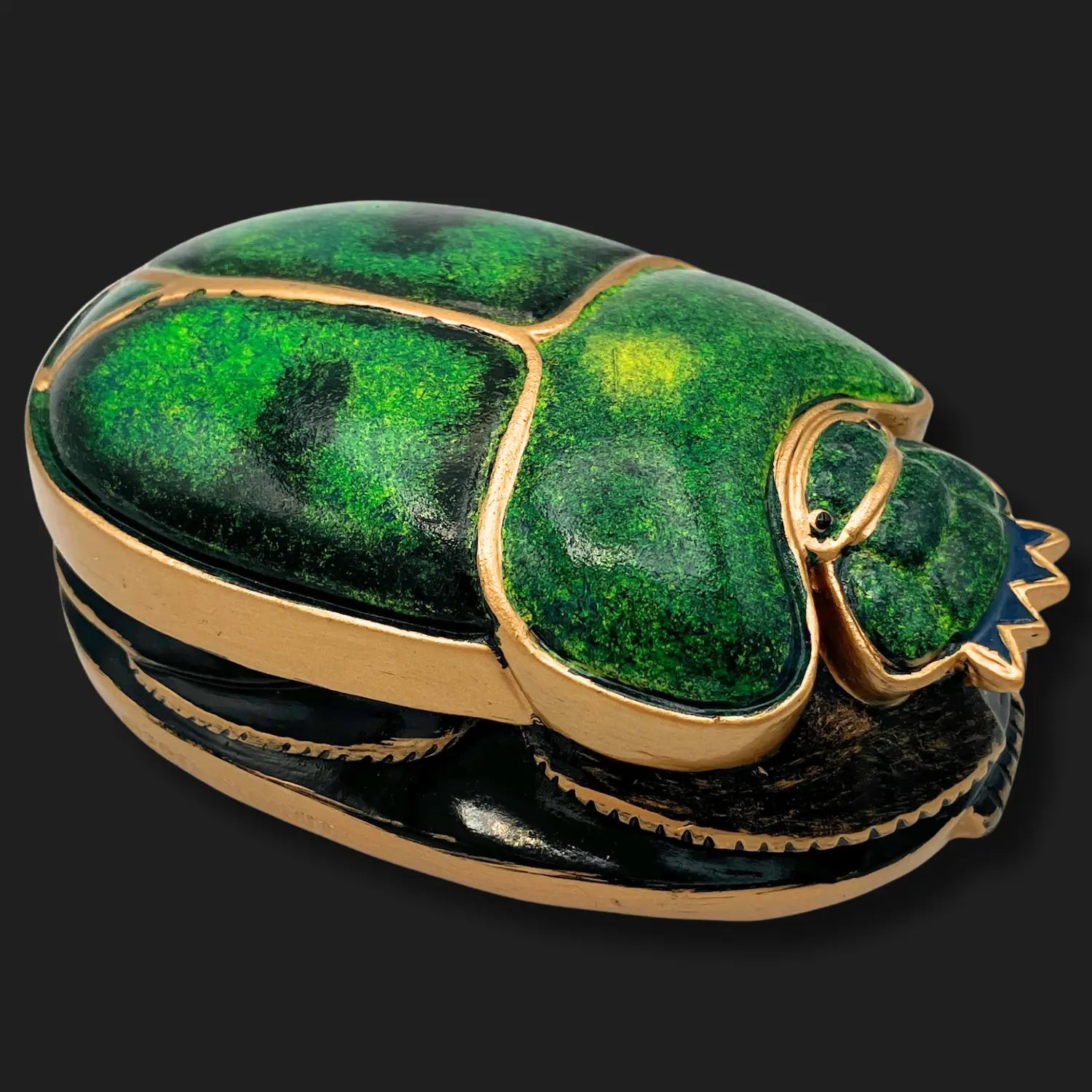 Side angle of emerald scarab beetle statue with gold accents, Egyptian relic design.