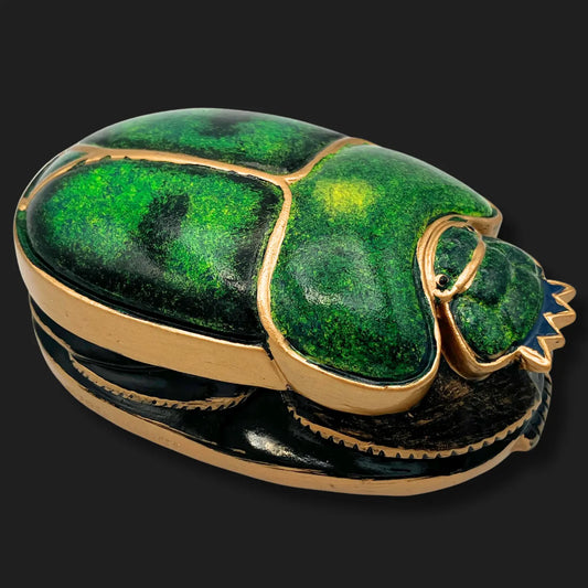 Side angle of emerald scarab beetle statue with gold accents, Egyptian relic design.