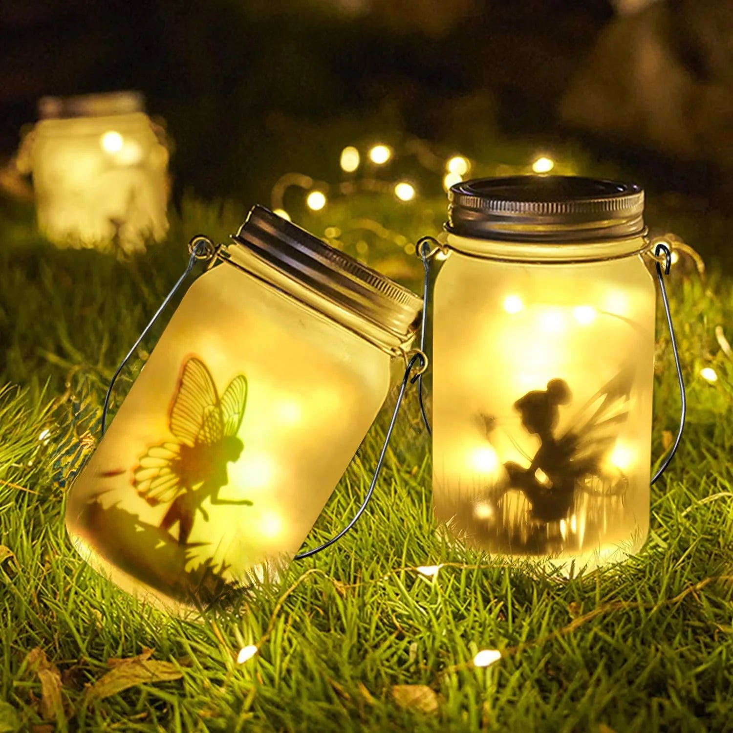Glowing fairy solar lanterns placed on grass at night, with warm yellow lights and whimsical fairy silhouettes