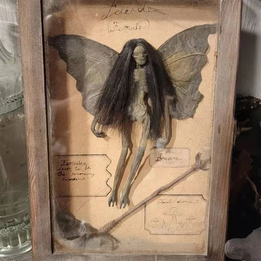 Handcrafted dark fantasy fairy specimen with long black hair and aged butterfly wings displayed in a wooden shadowbox