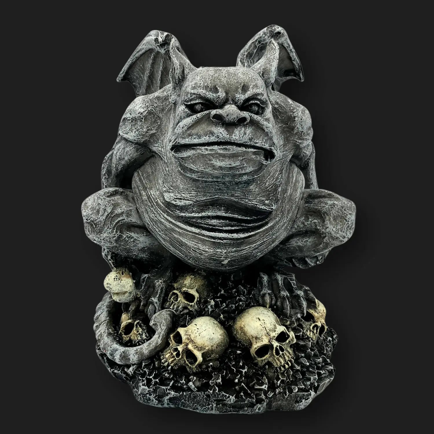 Front view of gothic gargoyle statue crouching on skull base, gothic décor.