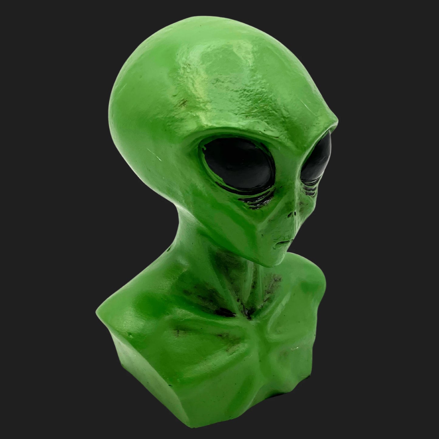 Side angle of green alien bust statue featuring large black eyes and elongated head