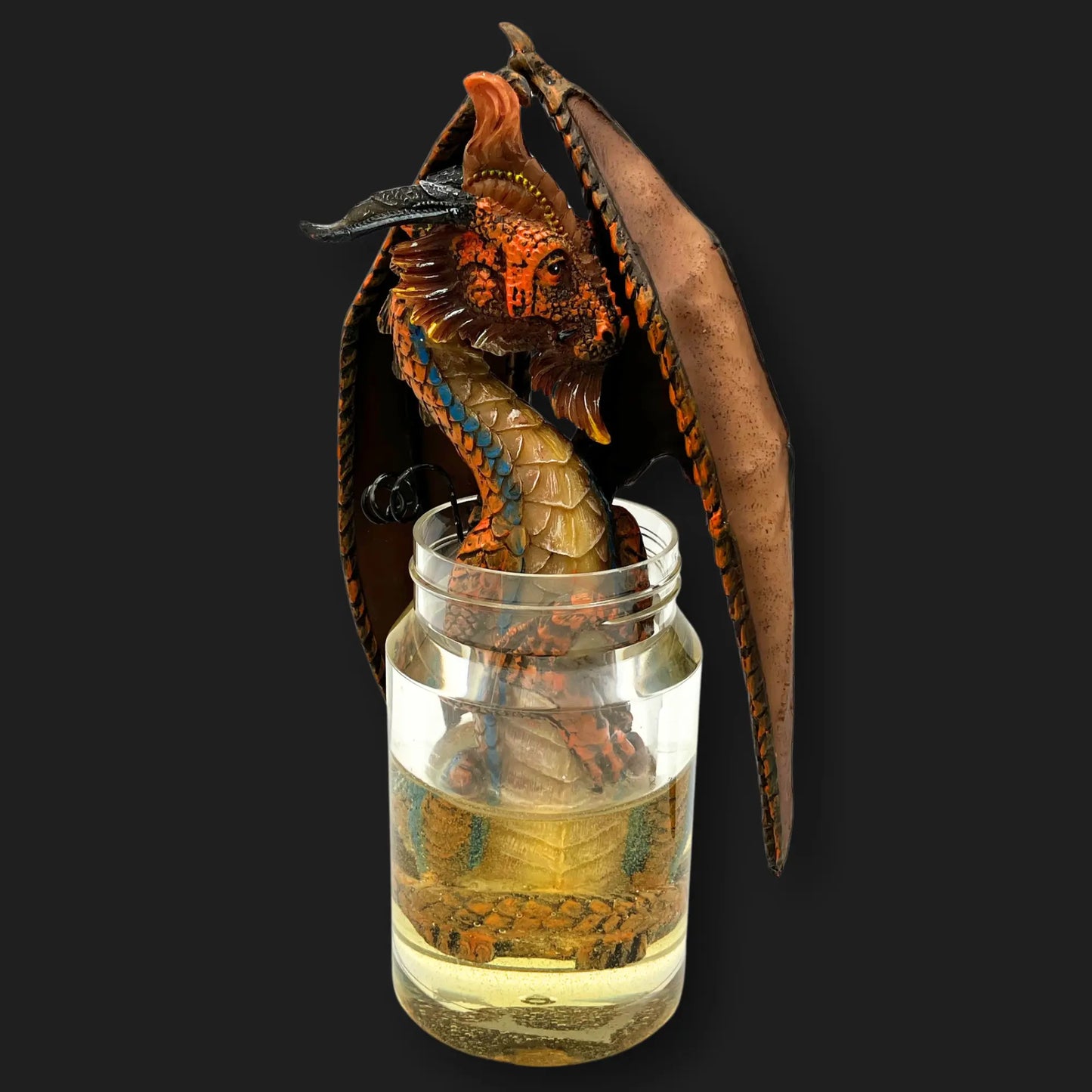 Front view of the moonshine dragon statue in jar with fiery orange scales fantasy décor.