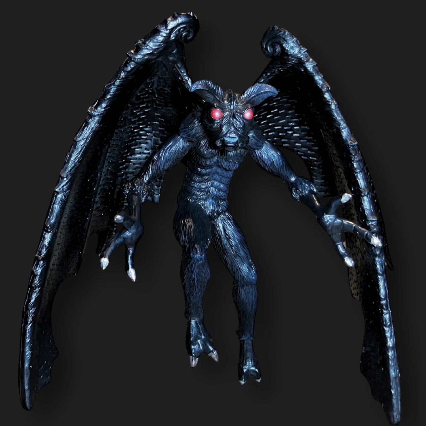 Dark Mothman figurine with glowing red eyes, textured black wings, and clawed feet.