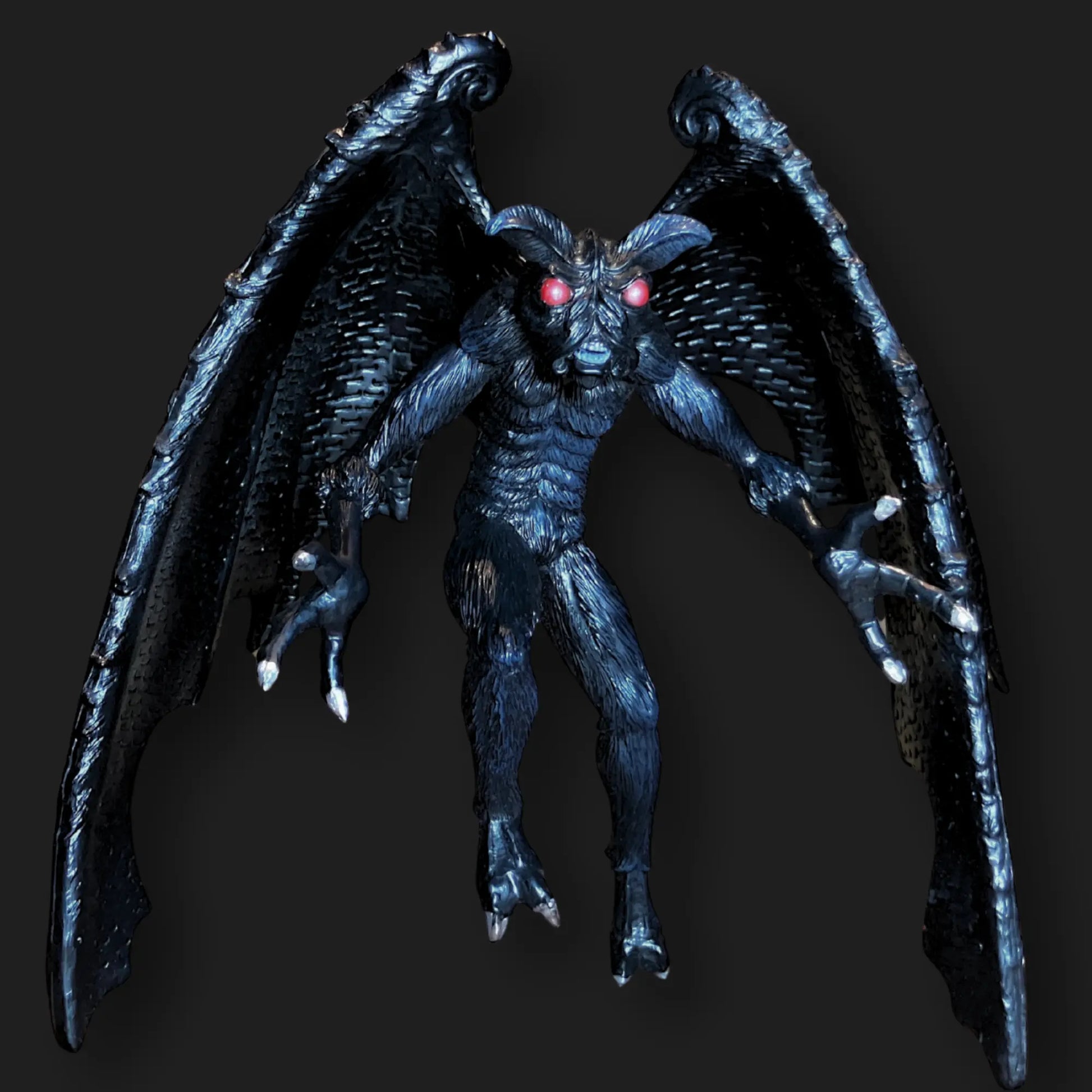 Dark Mothman figurine with glowing red eyes, textured black wings, and clawed feet.