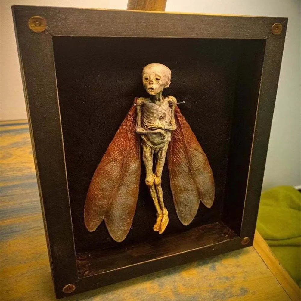 Side angle of eerie mummified fairy encased in a distressed wood shadow box, with gnarled limbs and ghostly wings visible through the glass
