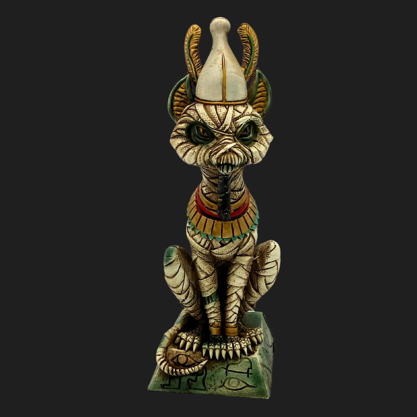 Front view of mummified Egyptian cat Osiris statue with crown, green eyes, and ornate base marked with hieroglyphs — ancient guardian figurine.