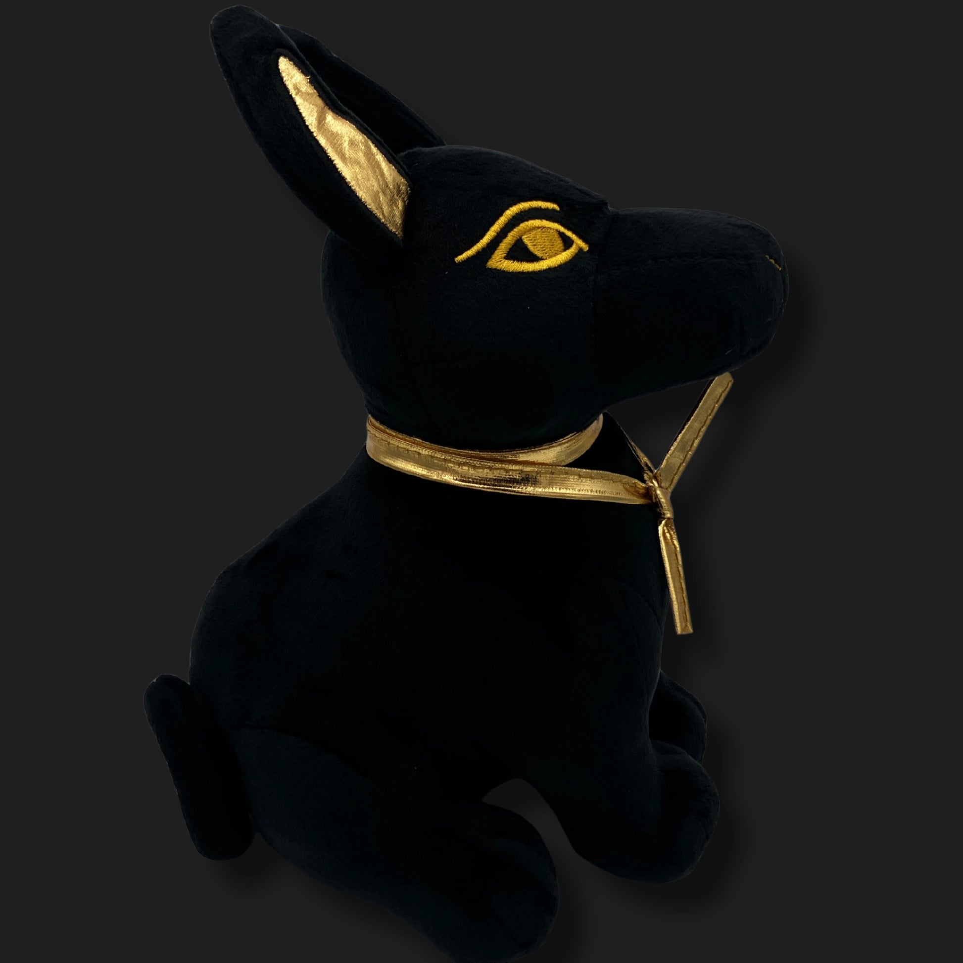 Side view of plush Anubis toy with golden ears, eyes, and collar – Egyptian jackal god collectible
