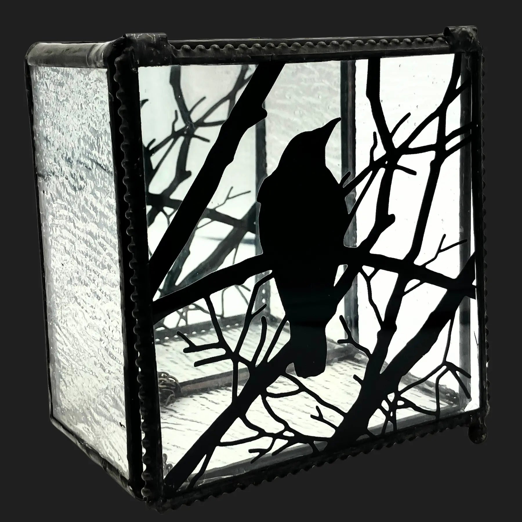 Side view of a raven art glass box with black silhouette design and mirrored base