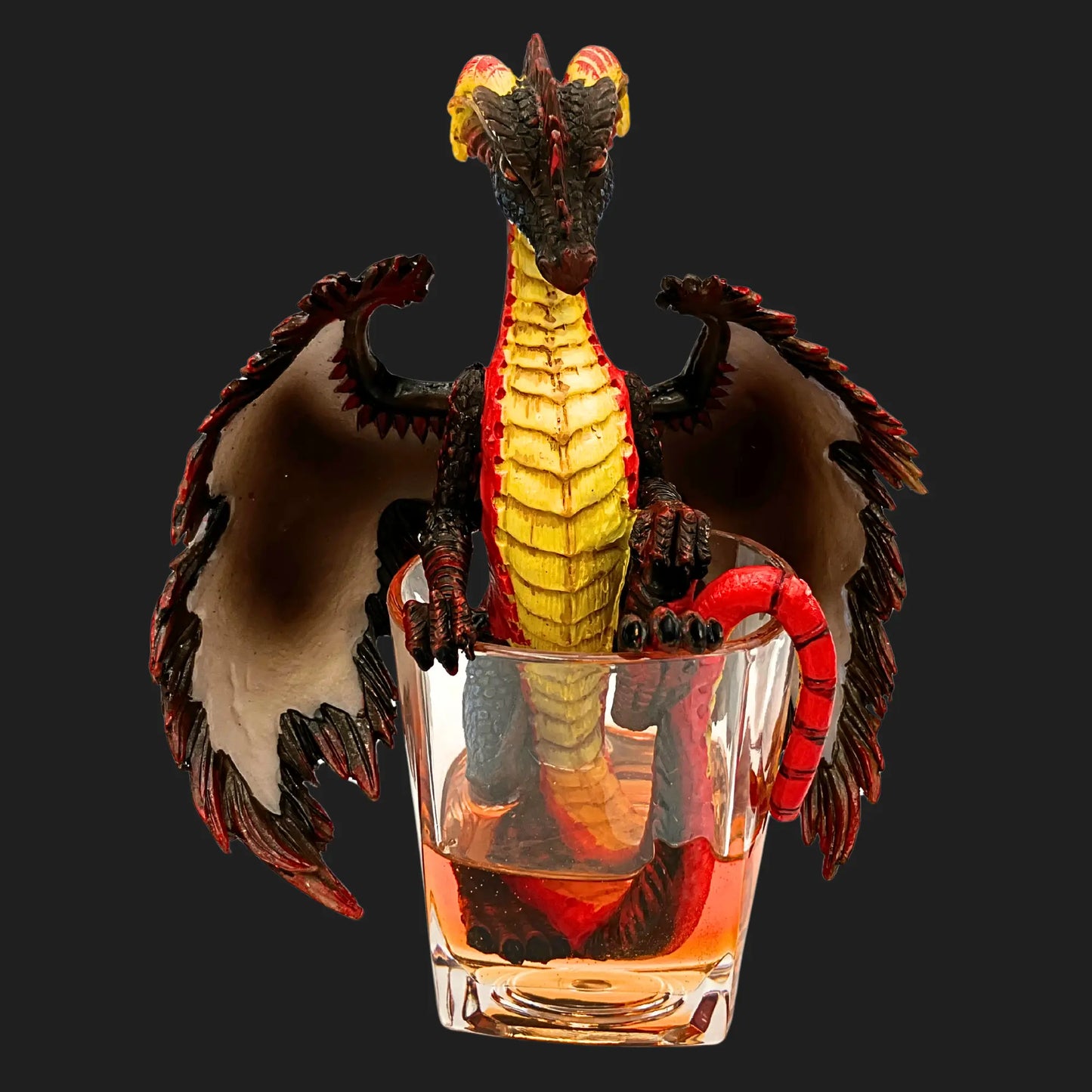Front view of rum dragon figurine in glass with fiery red and gold scales.