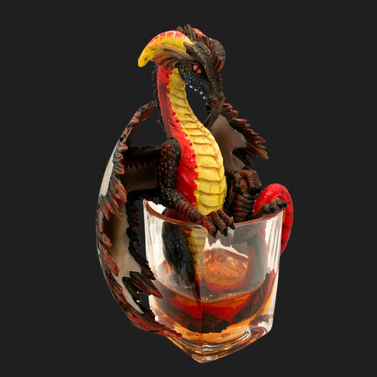 Side angle of rum dragon collectible in glass, red and gold fantasy décor.