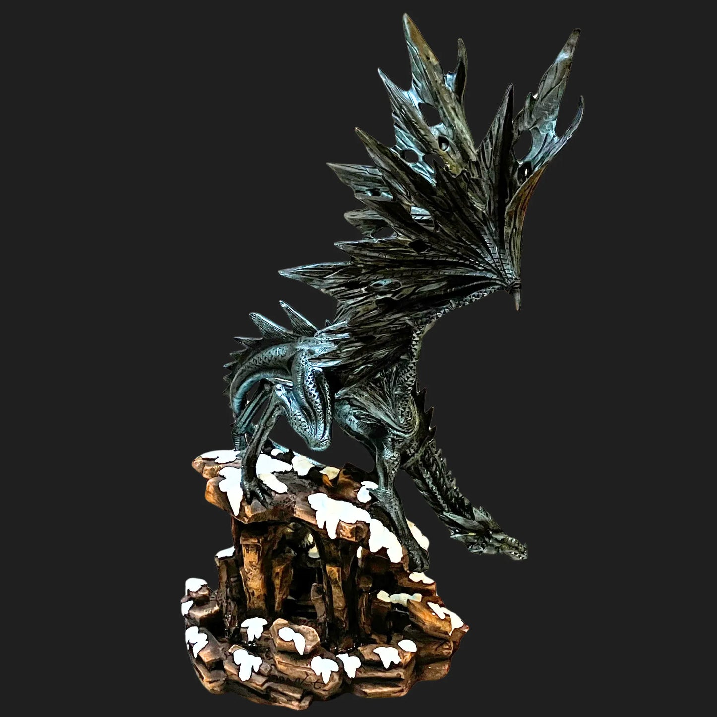 Tall black dragon guardian statue with jagged wings and snow-covered rocks
