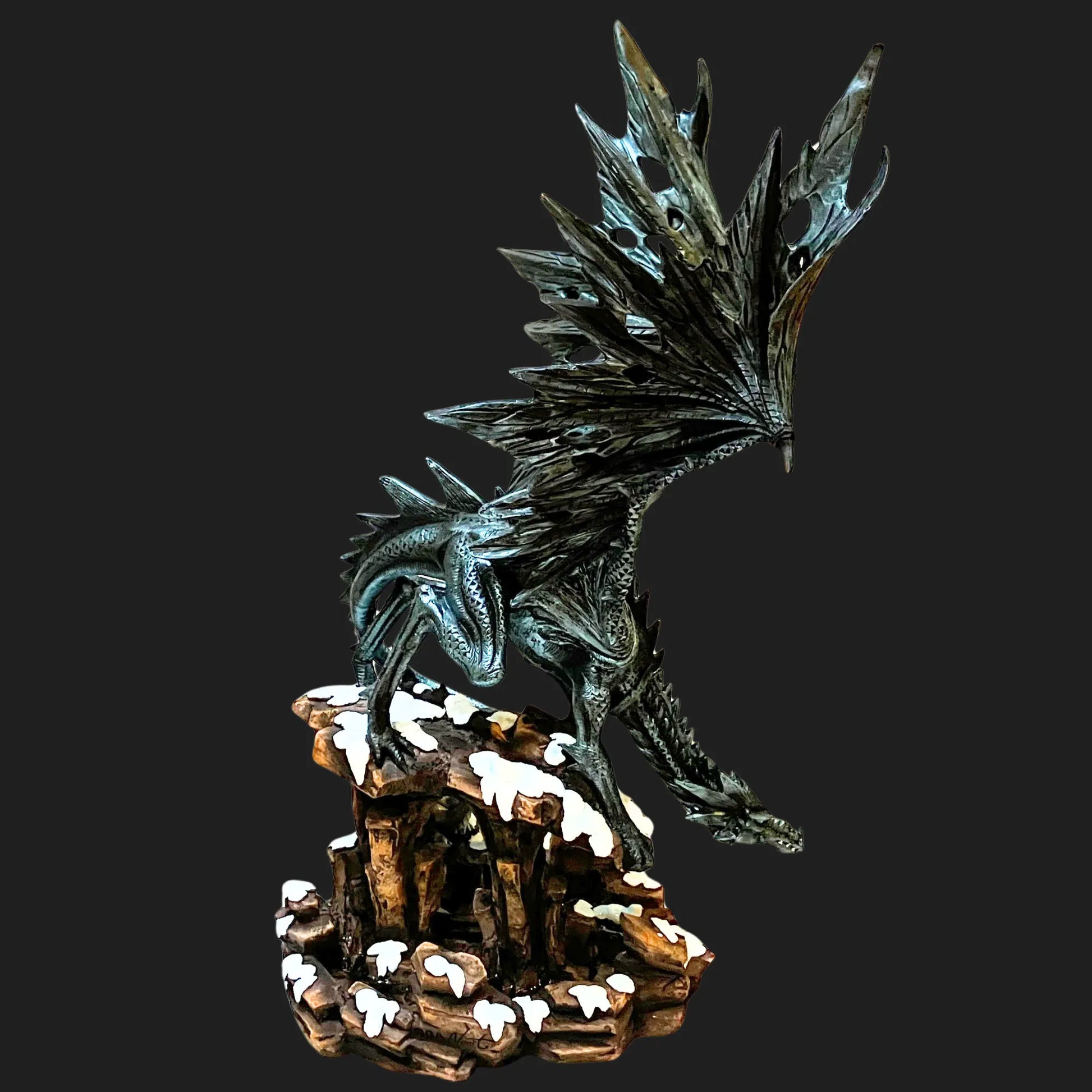 Tall black dragon guardian statue with jagged wings and snow-covered rocks