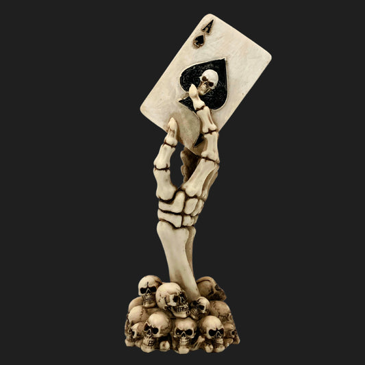Skeleton hand statue with skull base holding Ace of Spades card featuring skull emblem