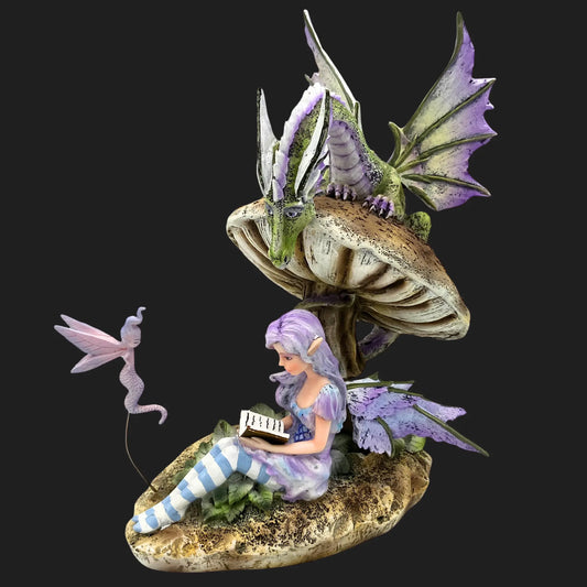 Storykeeper fairy figurine sitting under a mushroom, reading a book, with a green dragon perched above and a small sprite nearby.
