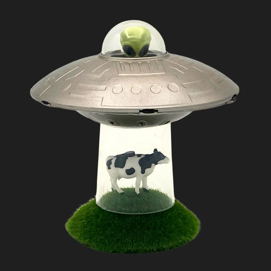Mini UFO toy with alien pilot abducting cow figurine on grass base