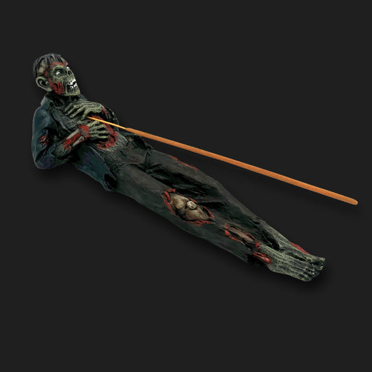 Zombie incense holder with incense stick placed through its chest, creepy horror décor piece